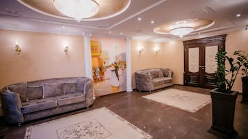 Eine großzügige Lobby mit zwei Sofas, einem großen Chandelier und einem Wandbild.