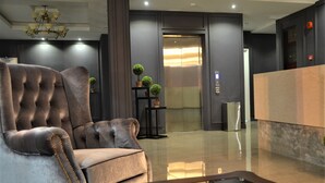 A modern lobby with a tufted armchair, a reception desk, and a glass coffee table. - TheBlanc Boutique Hotel (Malacca City)