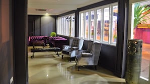 A lobby with a dark-colored sofa, a tufted armchair, and a tall vase. - TheBlanc Boutique Hotel (Malacca City)