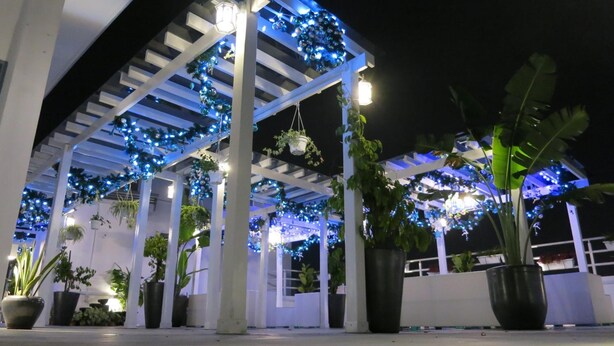 An outdoor covered area with white columns, blue string lights, and potted plants. - TheBlanc Boutique Hotel (Malacca City)
