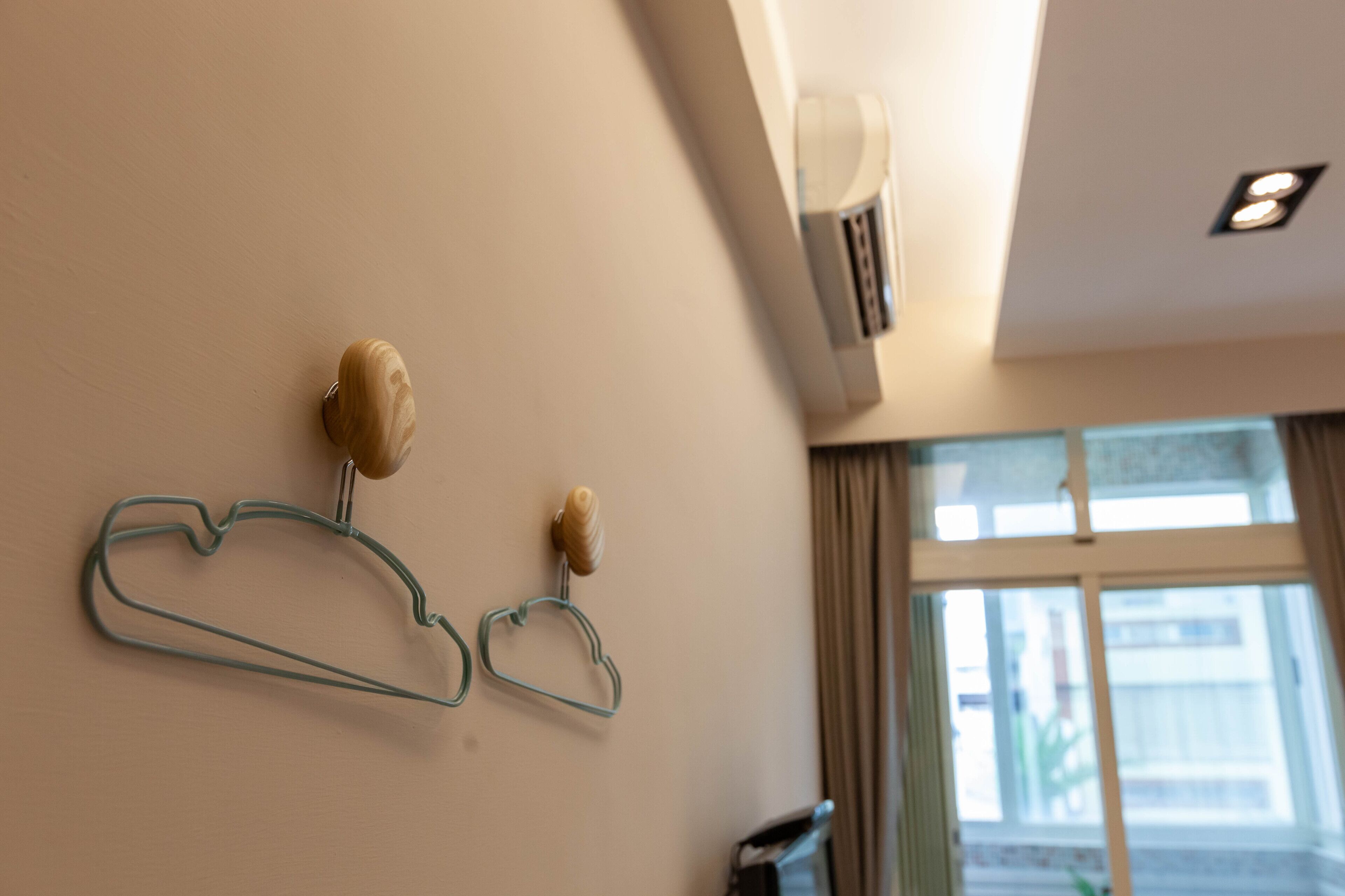 A room with a wall-mounted air conditioner, a window with curtains, and a wall-mounted light fixture.