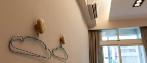 A room with a wall-mounted air conditioner, a window with curtains, and a wall-mounted light fixture.