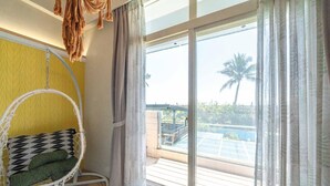 A room with a hanging chair, large windows, and a view of a pool and palm trees. - Taleocean (Hualien City)