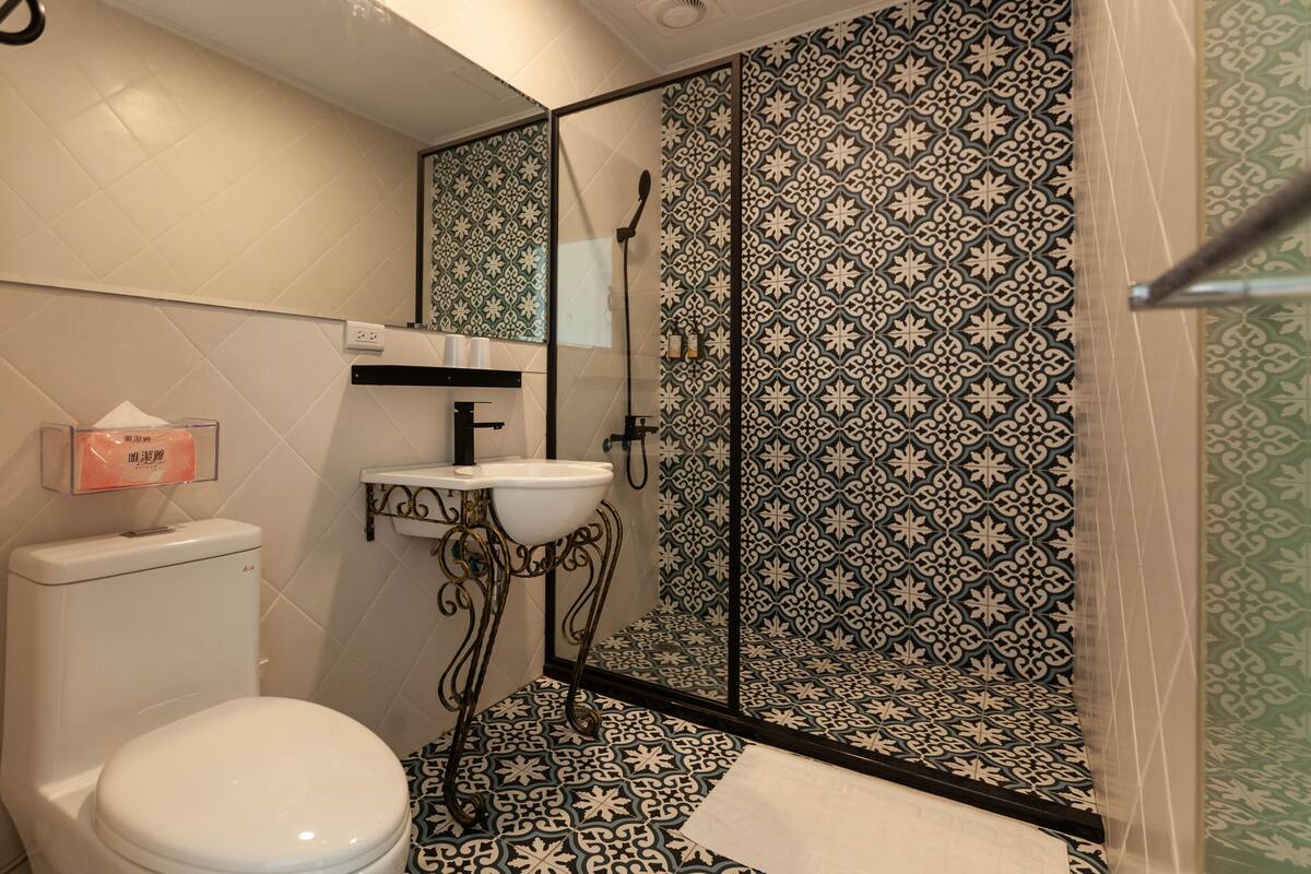 A bathroom with a toilet, sink, and shower area.
