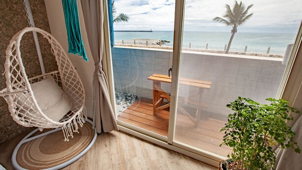 A balcony with a view of the sea, a hanging chair, a wooden table, and a potted plant. - Taleocean (Hualien City)