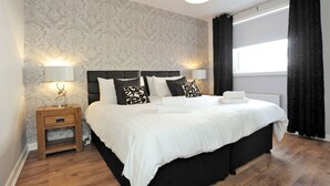A bedroom with a large bed, two bedside tables, a nightstand, and a window with curtains. - Home from Home Aberdeen (Aberdeen)