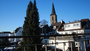 A church with a tall steeple, surrounded by residential buildings with traditional architecture. - Gästehaus beim Prinz (Kuerten)