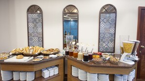 Un buffet proposant une variété de plats et de boissons, notamment des pains, des pâtisseries et une machine à café.