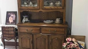 A wooden cabinet with glass doors, drawers, and a shelf with plates and a bicycle. - Chanathinat Place (Udon Thani)
