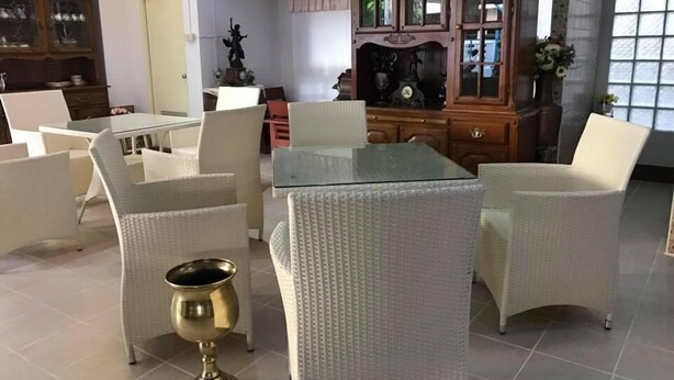 A spacious living area with a glass-top coffee table surrounded by white wicker chairs. - Chanathinat Place (Udon Thani)