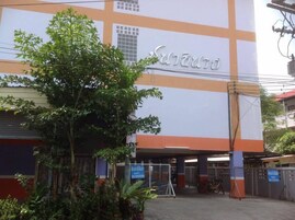 Un edificio con un letrero grande, una entrada con reja y algunas plantas en la parte frontal.