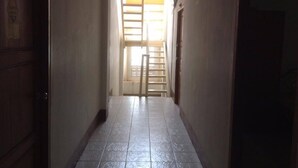 A hallway with a tiled floor leading to a door with a window. - Chanathinat Place (Udon Thani)