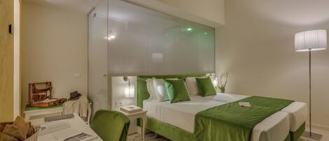 A hotel room with a large bed, a desk with a chair, a small table, and a lamp.
