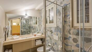Un baño moderno con cabina de ducha de vidrio, un espejo grande y un mueble de tocador color beige con lavabo y espacio para toallas.