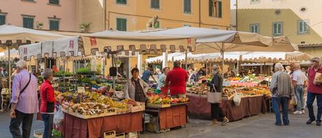 An outdoor market with various stalls selling fruits and vegetables.