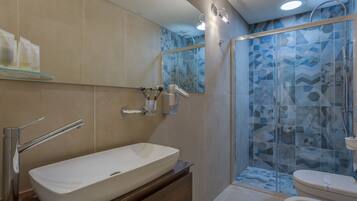 Une salle de bain moderne avec un grand lavabo blanc, une douche à parois de verre et des toilettes.