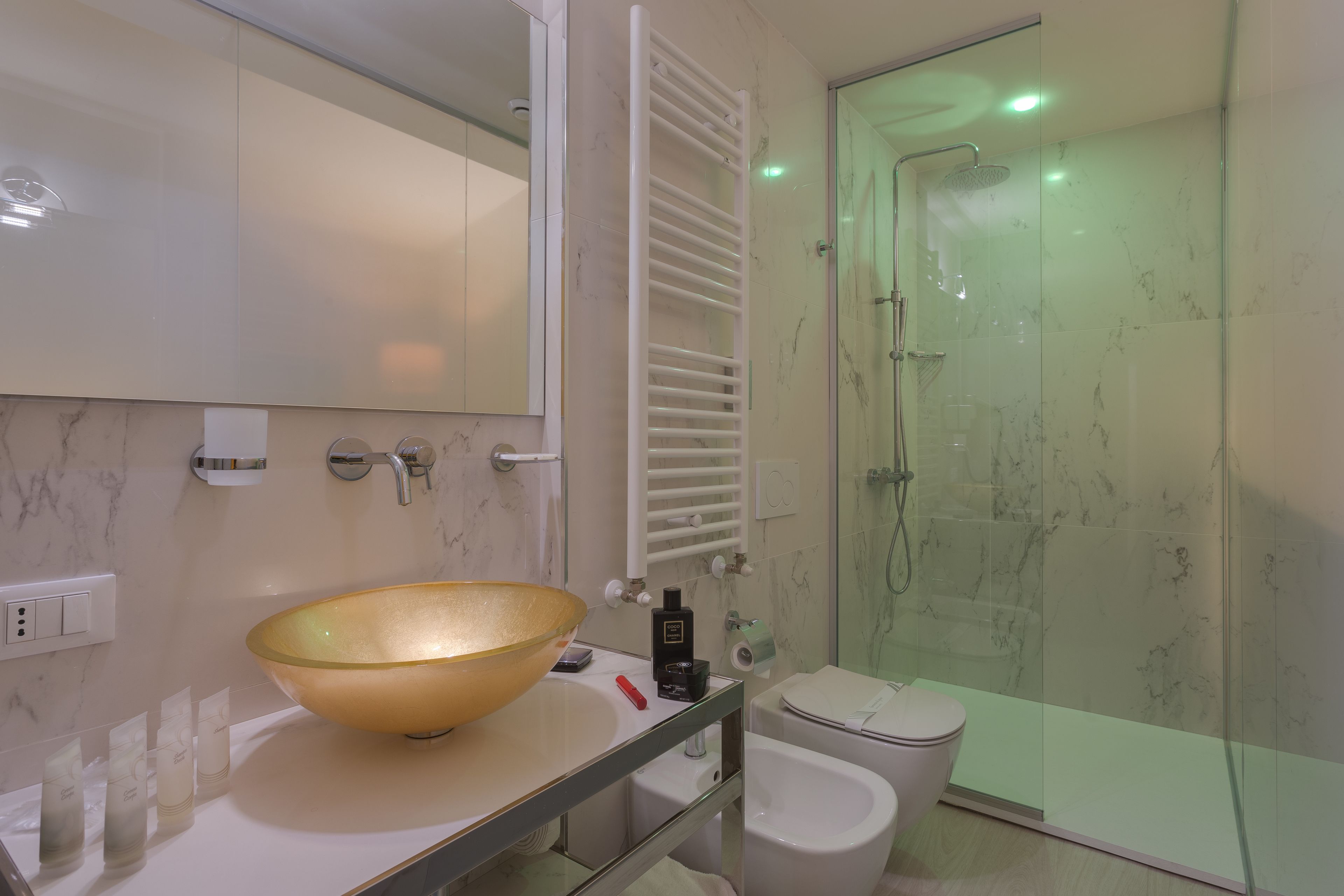 A modern bathroom with a large glass bowl sink, a toilet, and a glass-enclosed shower.