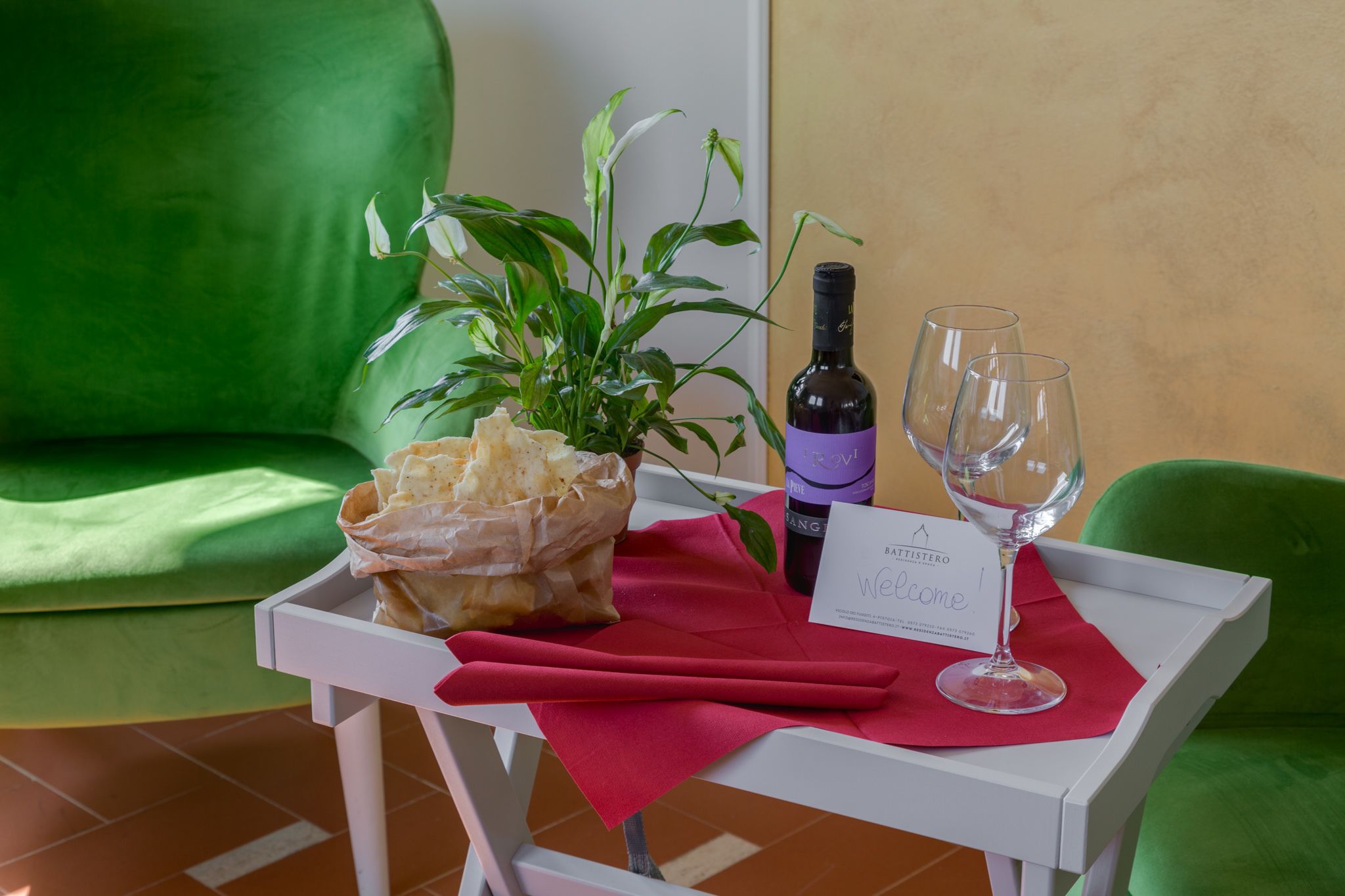 Una mesa con una botella de vino, dos copas, una tarjeta de nombre y una planta.