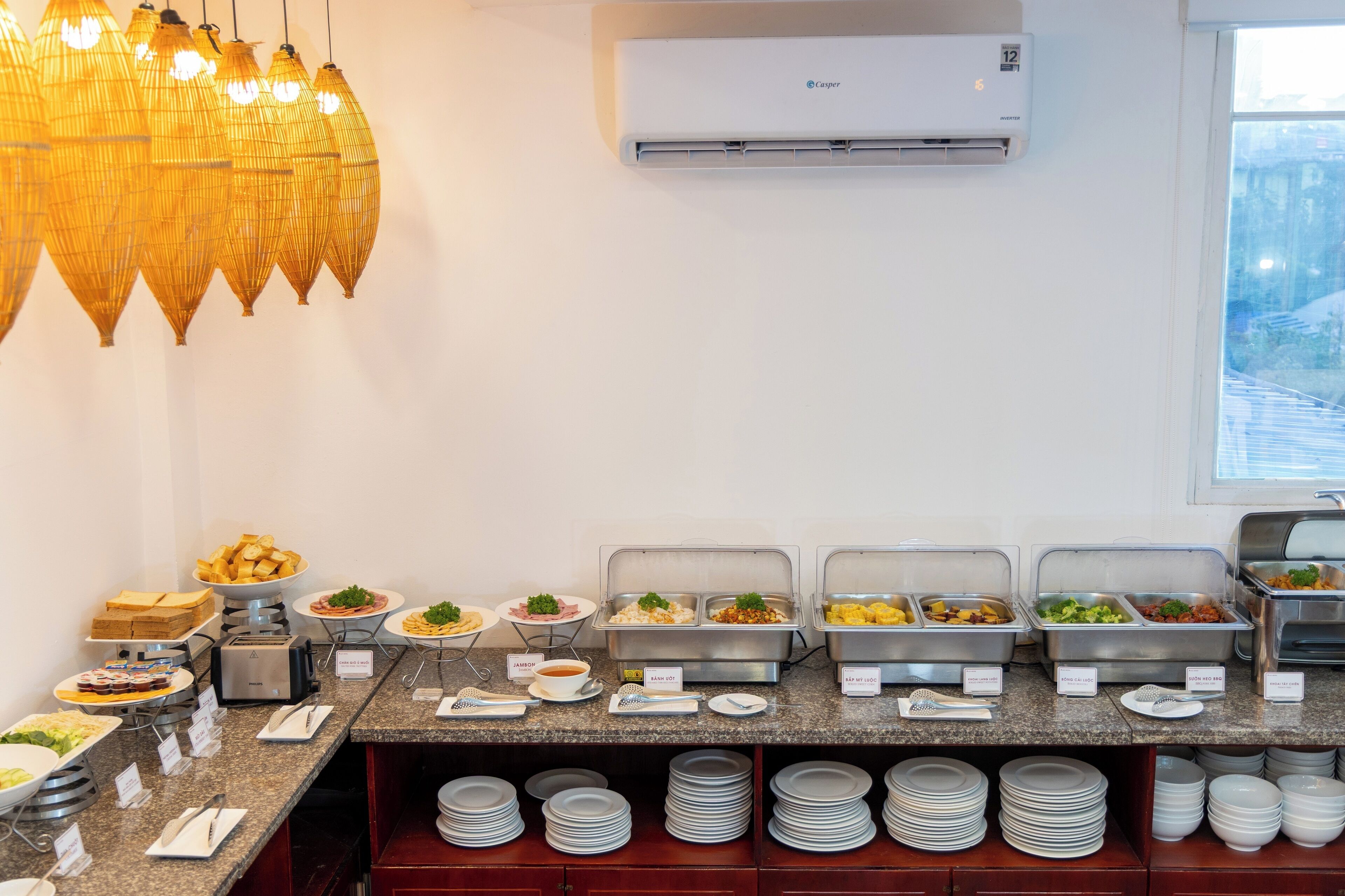 A buffet setup with various food stations, a coffee machine, and a stack of plates.