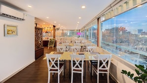 A dining area with white chairs and tables, a decorative wall, and a view through large windows. - A25 Premium Hotel - 20 Bui Thi Xuan (Ho Chi Minh City)