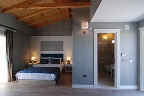 A bedroom with a large bed, two bedside tables with lamps, a wooden ceiling, and a bathroom visible through an open door. - Alacati The Design Hotel (Cesme)
