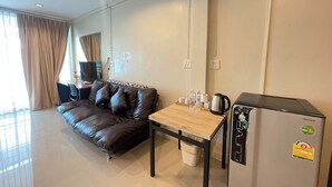 A modern living room with a leather sofa, a small table with a kettle, and a refrigerator. - Bann Lhong Rak Krabi (Krabi)