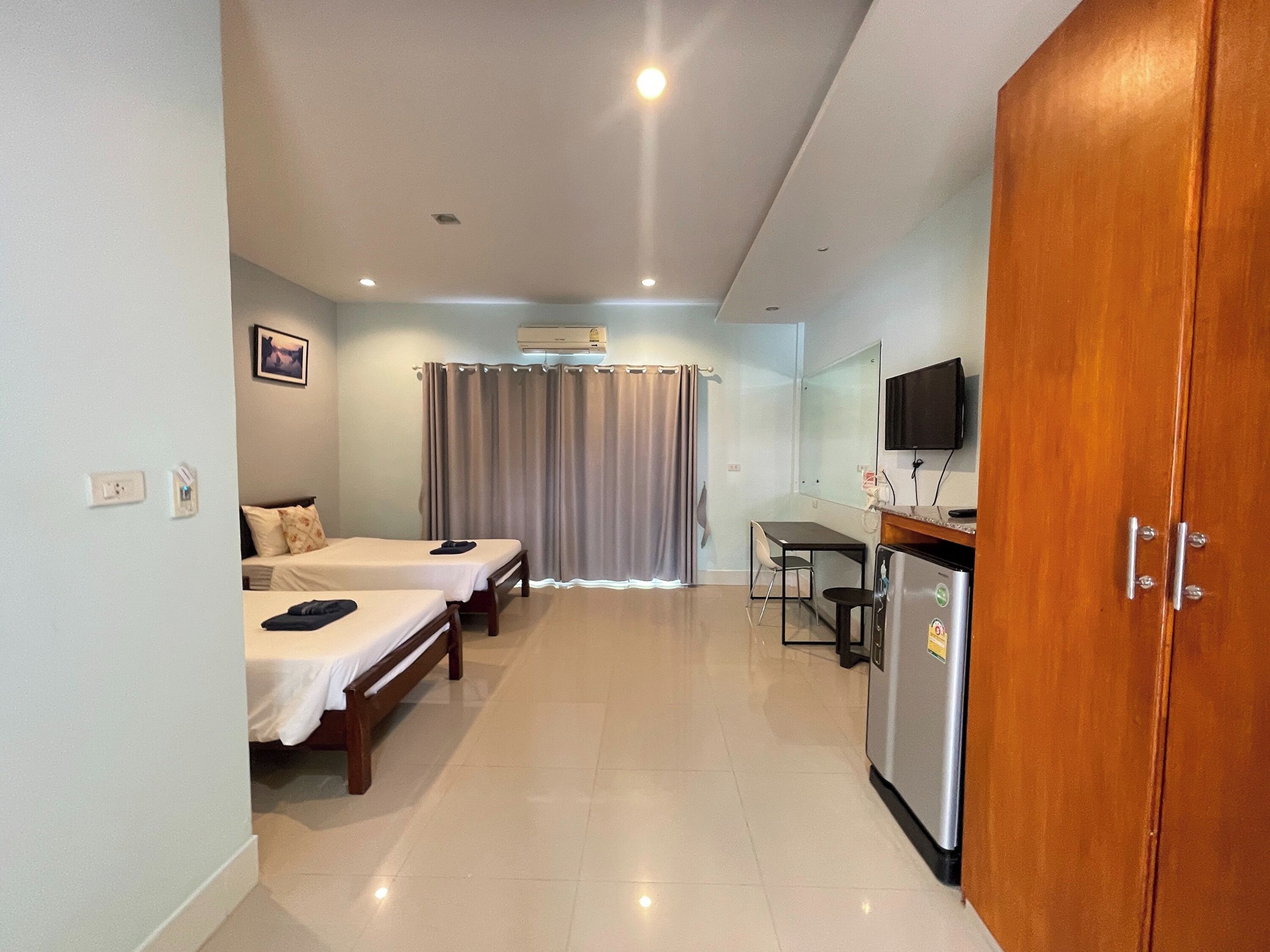 A hotel room with two beds, a desk, a television, and a wardrobe.