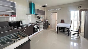 A modern kitchen with a dining area, stainless steel appliances, and a teal-colored hood. - Bann Lhong Rak Krabi (Krabi)