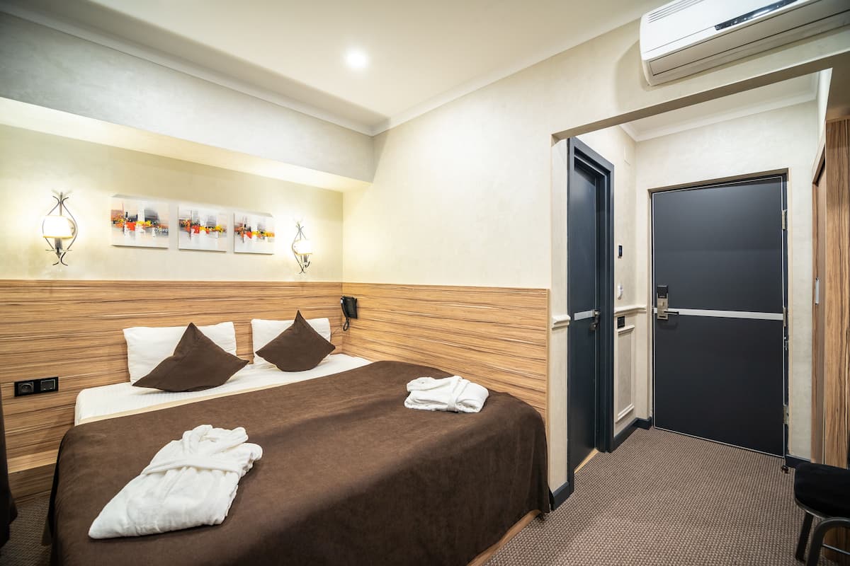 A hotel room with a bed, a door, and wall-mounted artwork.