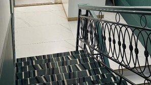Uma receção com recepcionista, uma escadaria com guarda-corpo de metal e uma parede com logótipo e texto.