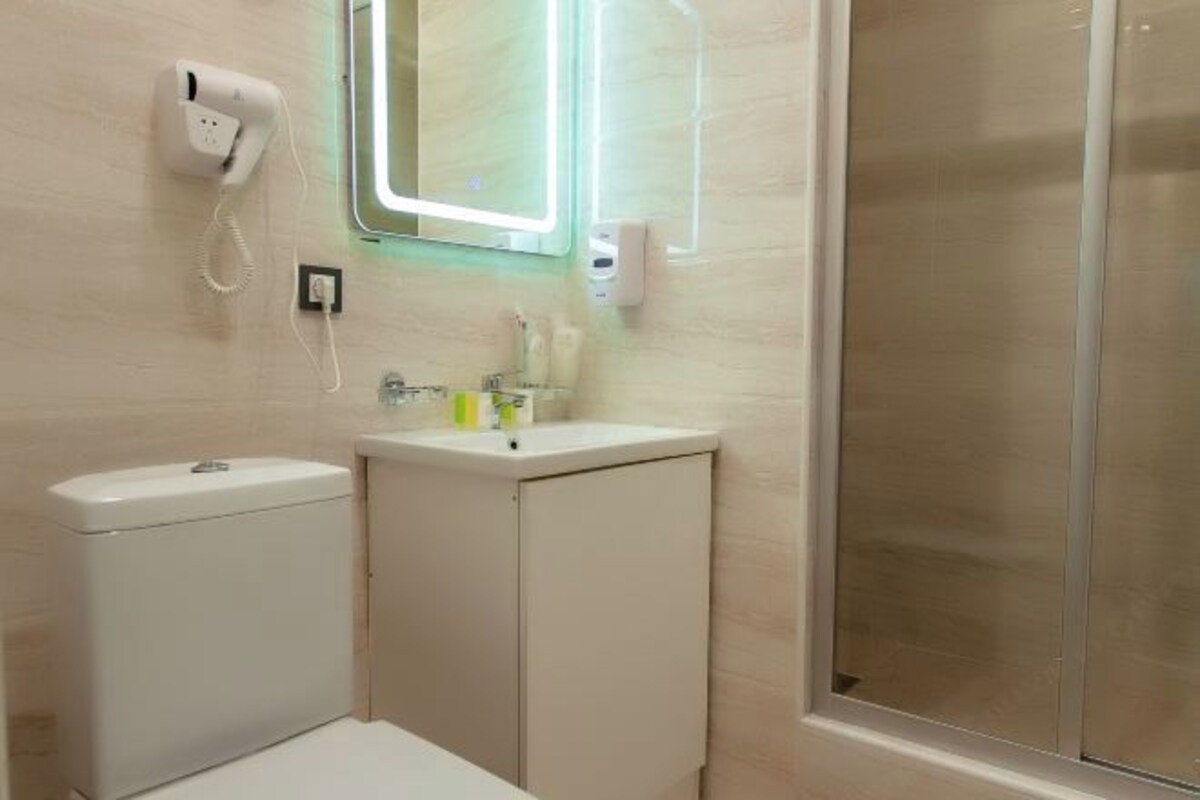 A bathroom with a toilet, sink, and a glass shower enclosure.