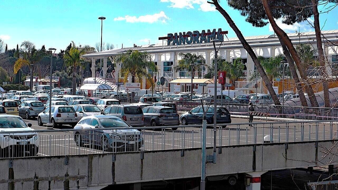 A busy shopping center with a large building labeled "PANORAMA" in the background.