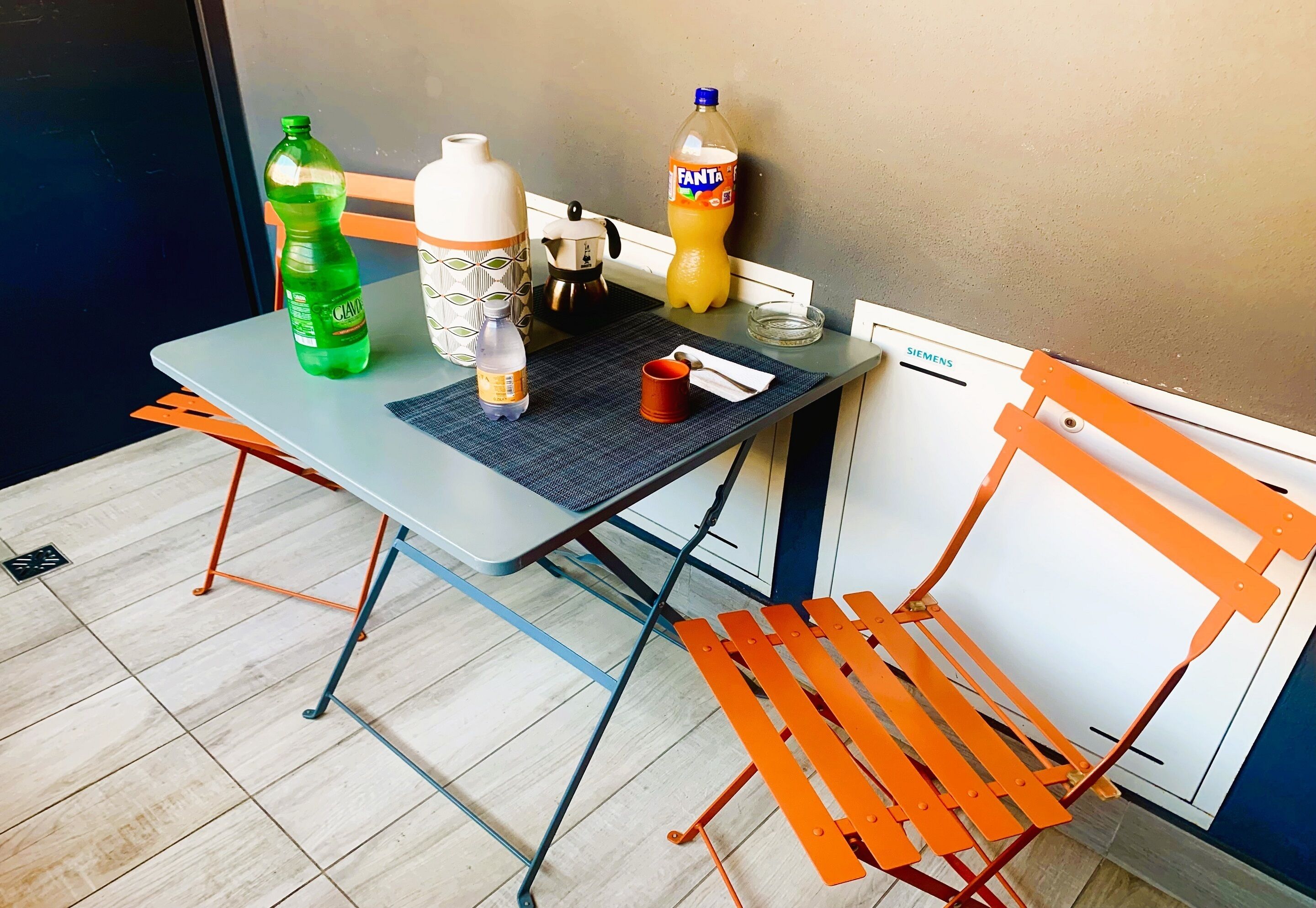 A table with a water bottle, a mug, a thermos, a glass, and a Siemens refrigerator.