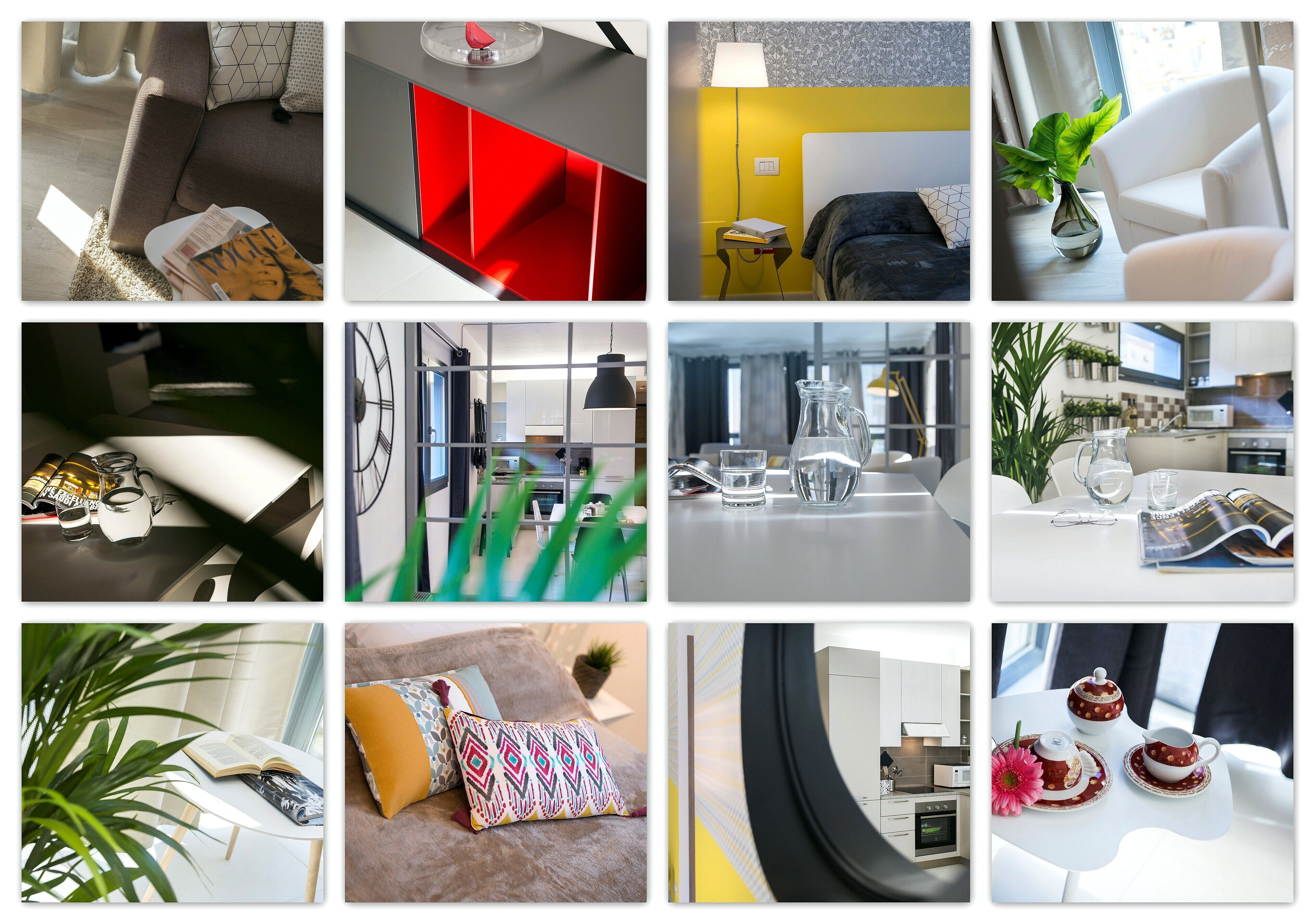 Habitación de hotel moderna con sofá, pared de acento roja, zona de comedor con mesa y sillas, y cocina.