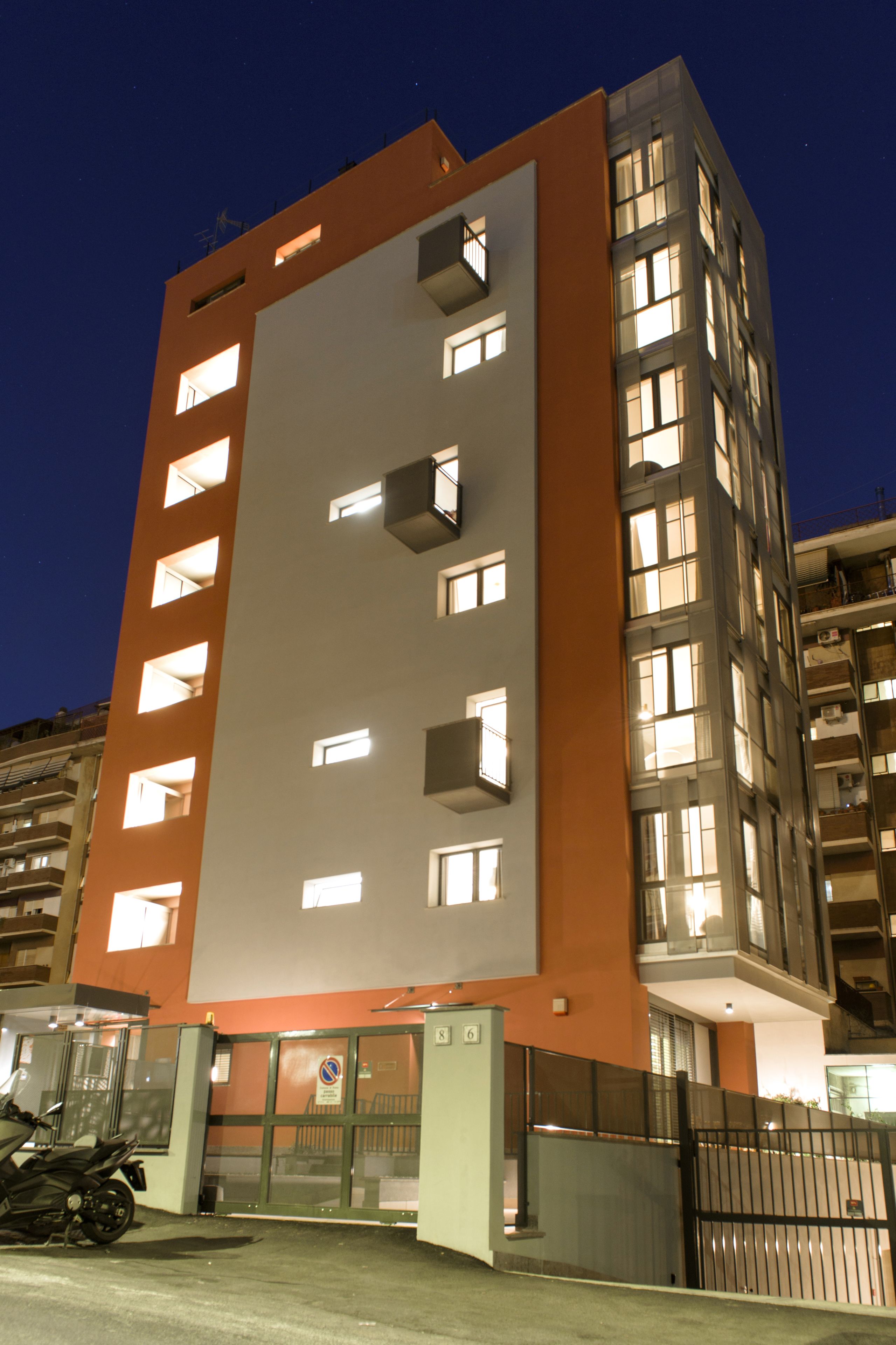 A multi-story building with illuminated windows and a gated entrance.