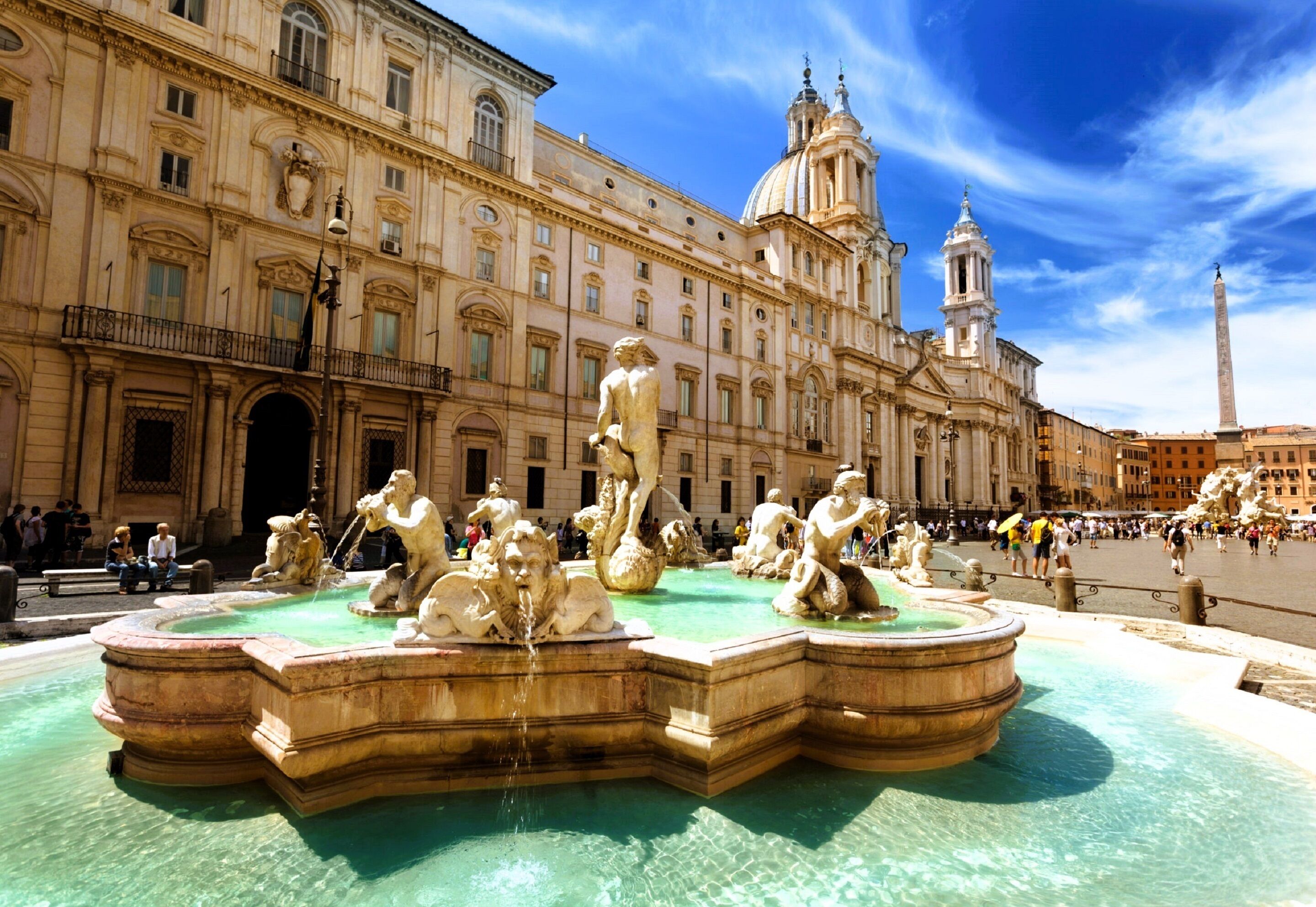 A historic fountain with multiple statues in a public square, surrounded by classical architecture.