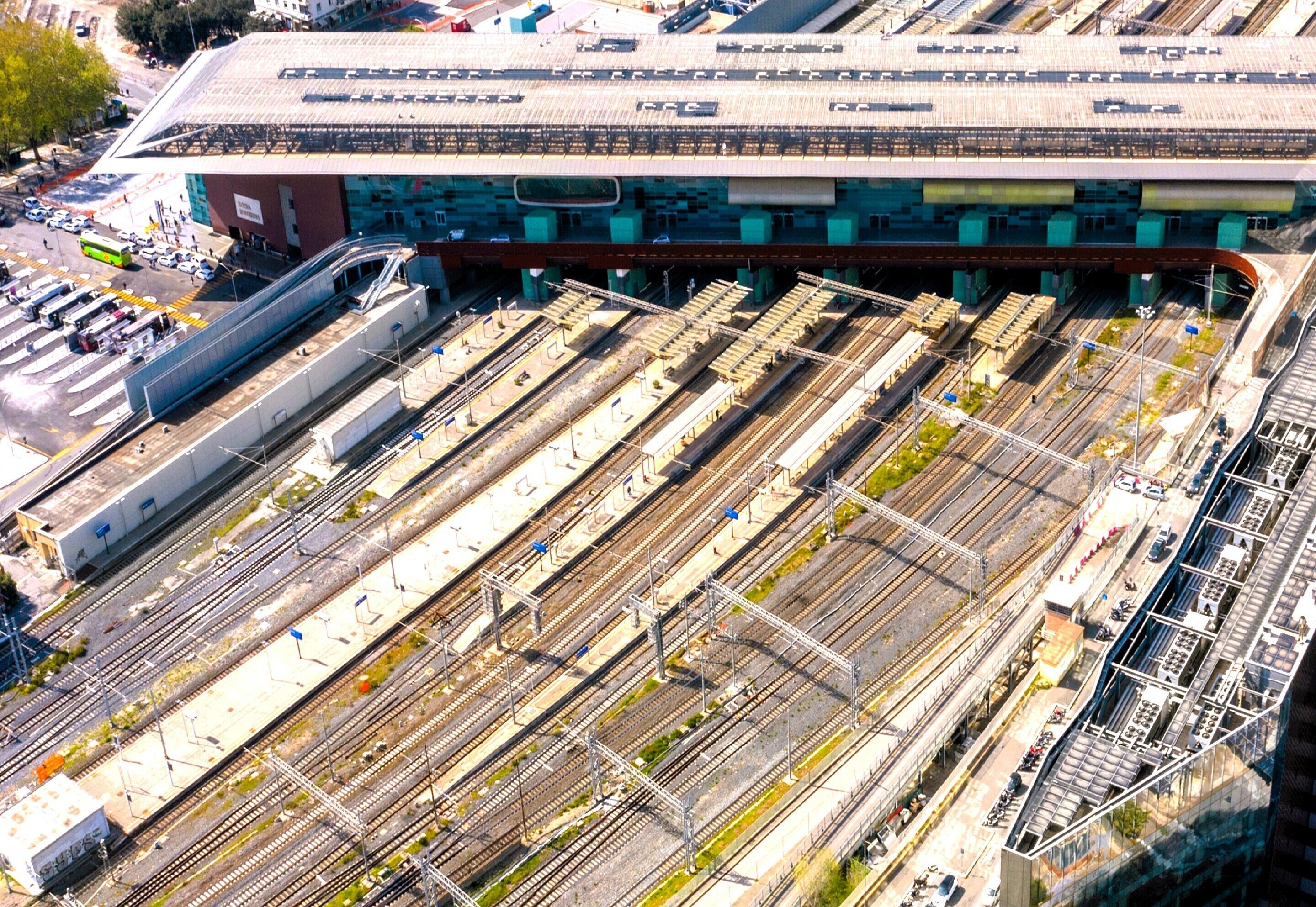 An aerial view of a train station with multiple tracks and a large building with a sloped roof.