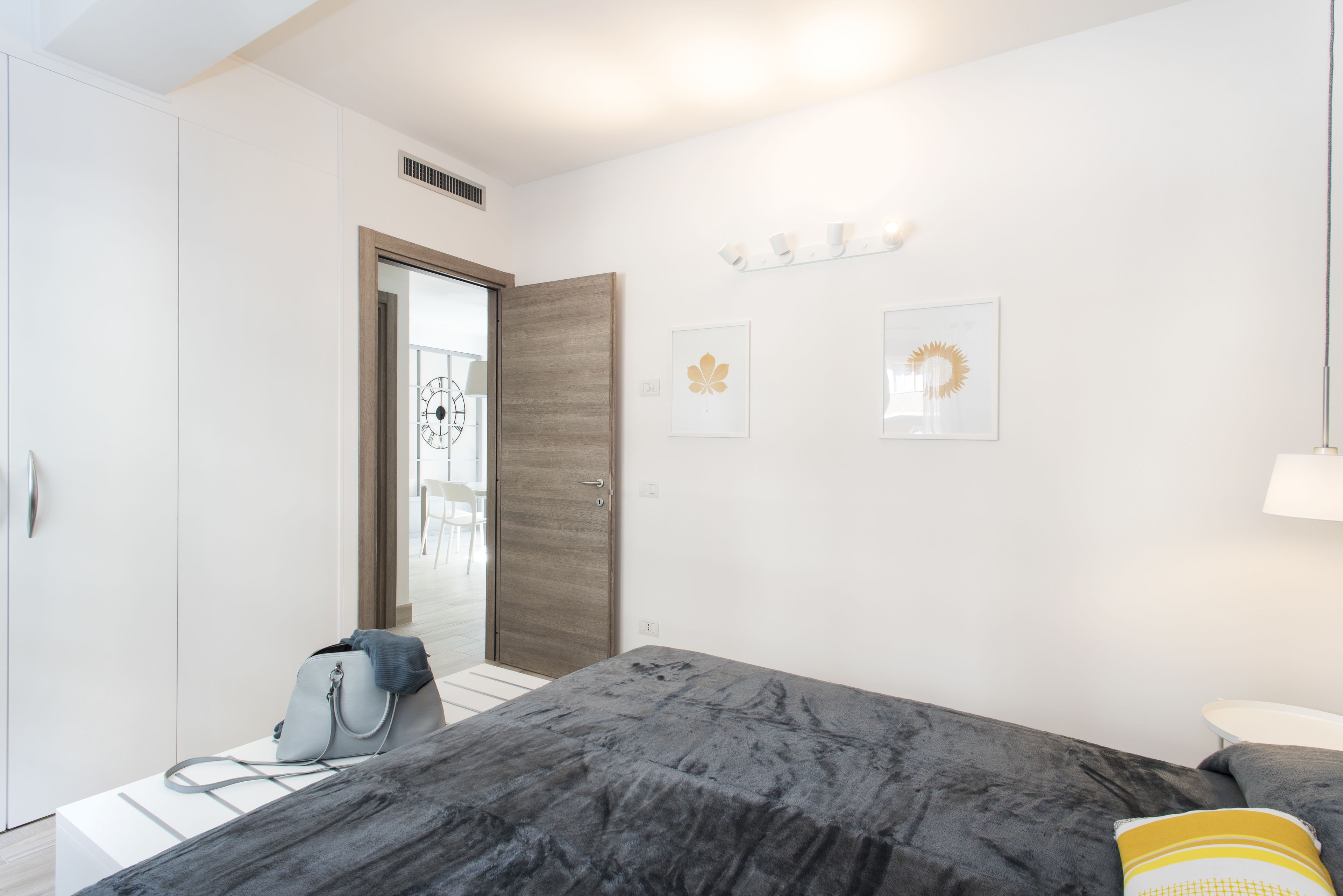 Un dormitorio moderno con cama, armario, mesita de noche y lámpara.