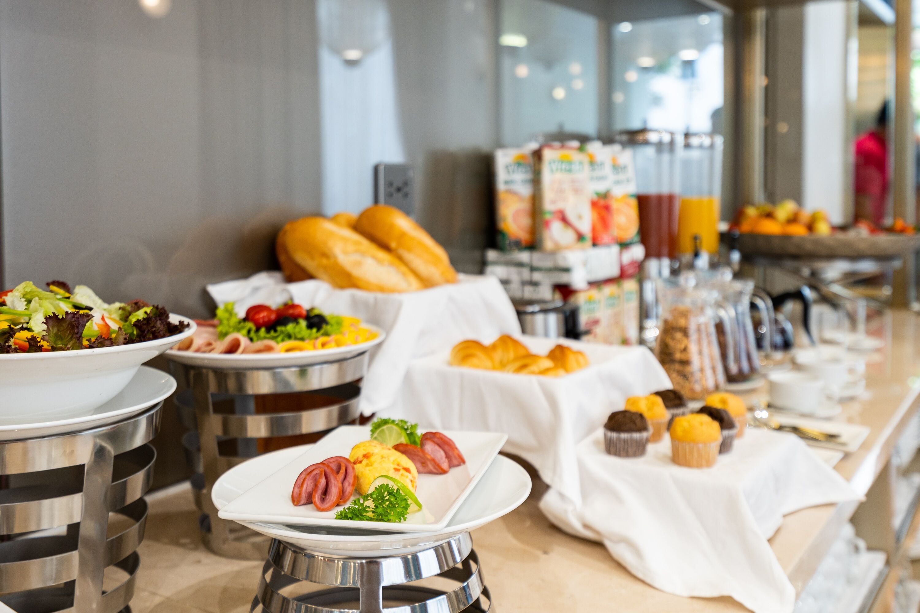 Un bufé con diversas opciones de comida, como ensaladas, pasteles y muffins.