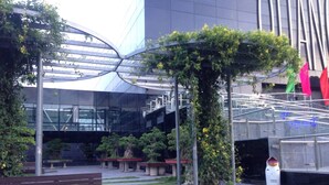 An outdoor area with a modern building, a wooden bench, and a sculpture. - Kocmoc Ha Long (Ha Long)