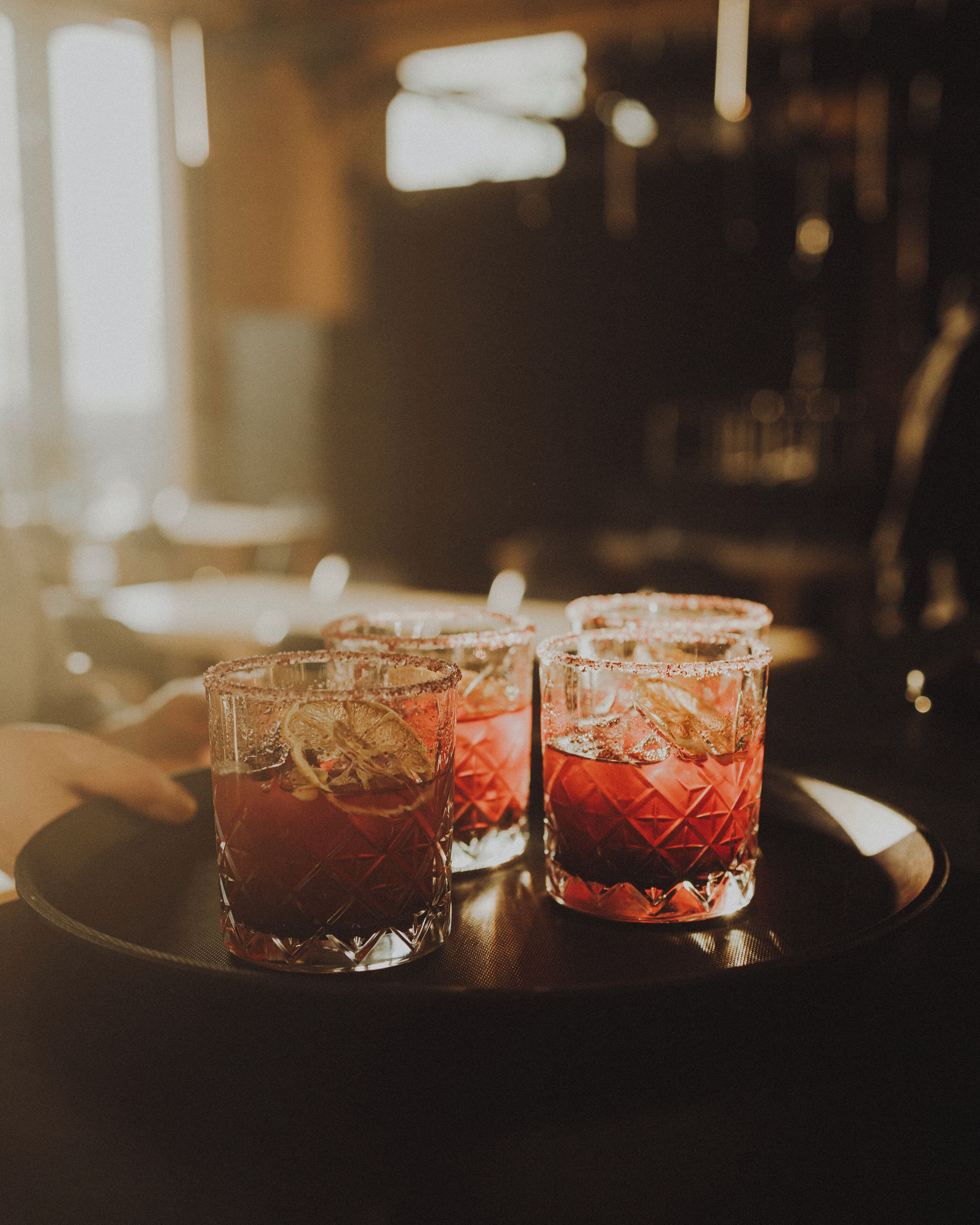 Three glasses of red beverage on a tray.