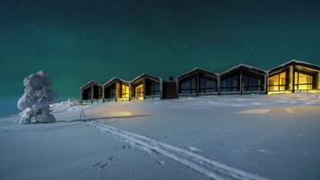 A row of snow-covered cabins with illuminated windows against a starry night sky.