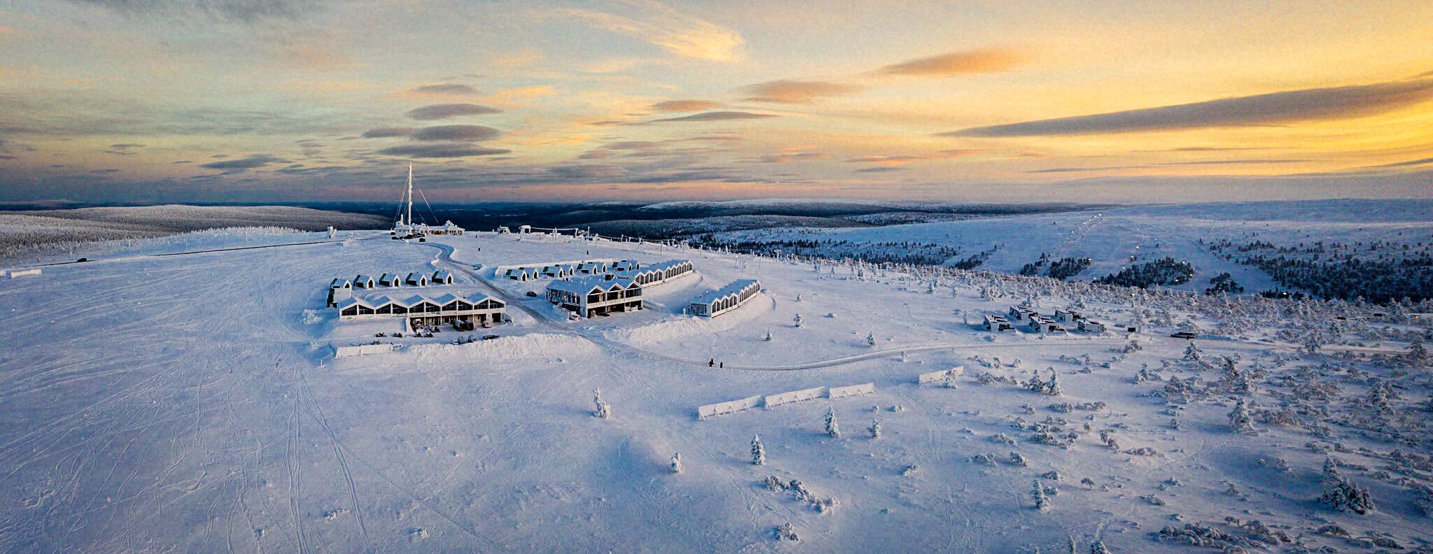 Een besneeuwd landschap met een groot landhuis met meerdere gebouwen en een skilift.