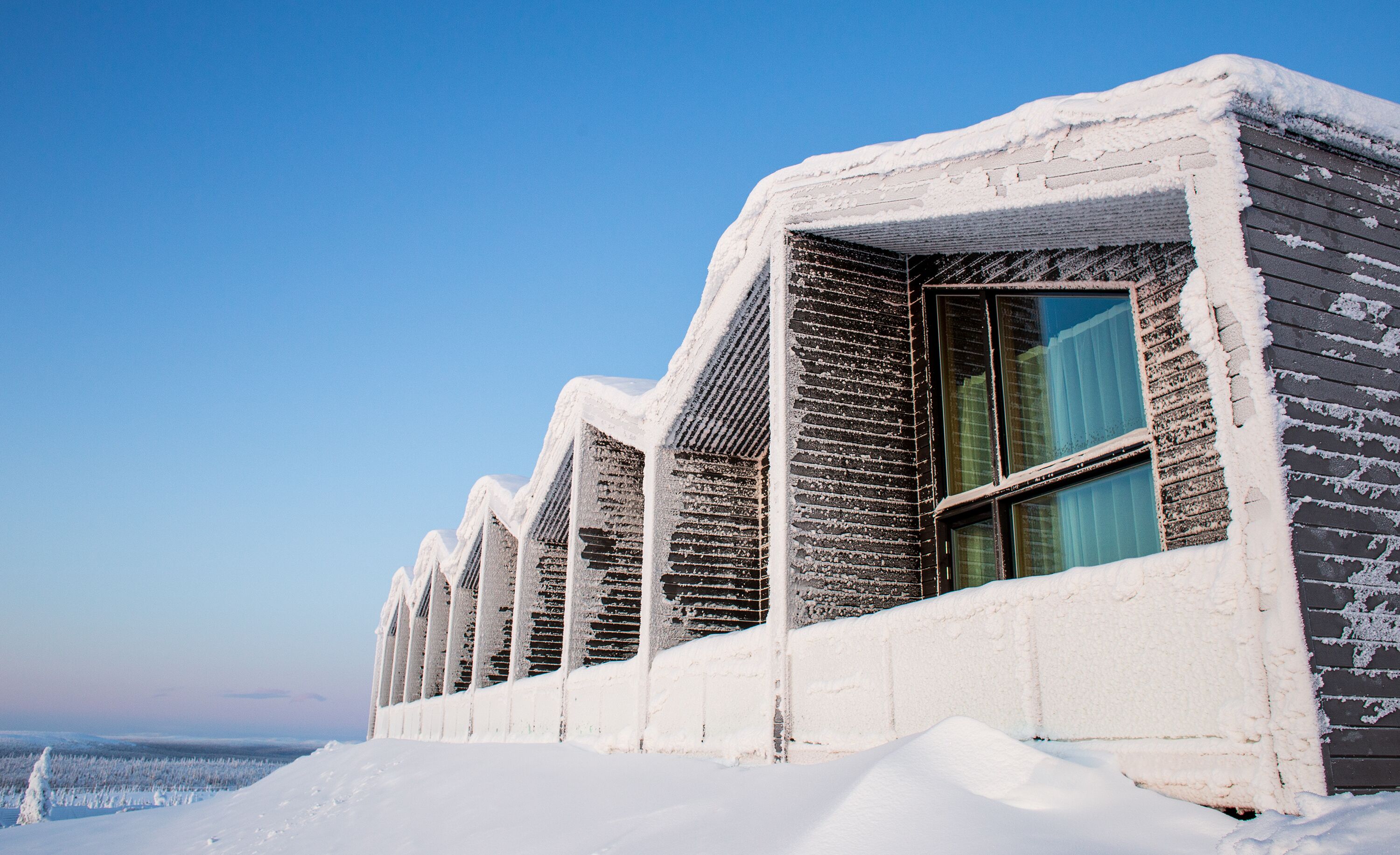 Eine Reihe von schneebedeckten Gebäuden mit großen Fenstern, wahrscheinlich ein Hotel oder Resort.