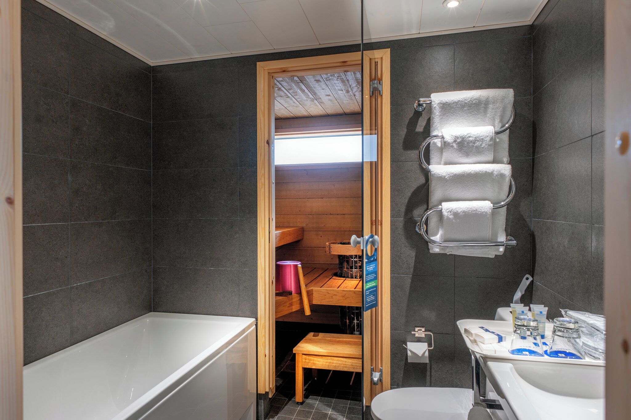 A modern bathroom with a bathtub, a wooden bench, and a sink.