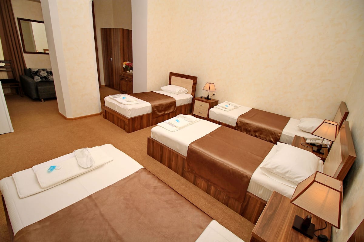 Una habitación de hotel con tres camas, una zona de estar y un baño.