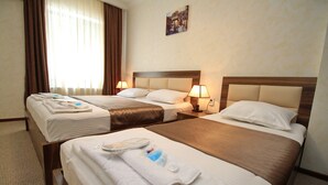 A hotel room with two beds, each with a headboard, bedside tables with lamps, and towels on the beds. - villa old sololaki (Tbilisi)