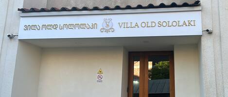 Entrada de un edificio con un cartel que dice "Villa Old Sololaki" y un símbolo de prohibido fumar.