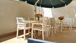 An outdoor patio with a table and chairs under a large umbrella. - villa old sololaki (Tbilisi)