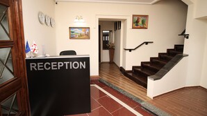 A reception area with a reception desk labeled "RECEPTION," a staircase, and a hallway leading to another room. - villa old sololaki (Tbilisi)